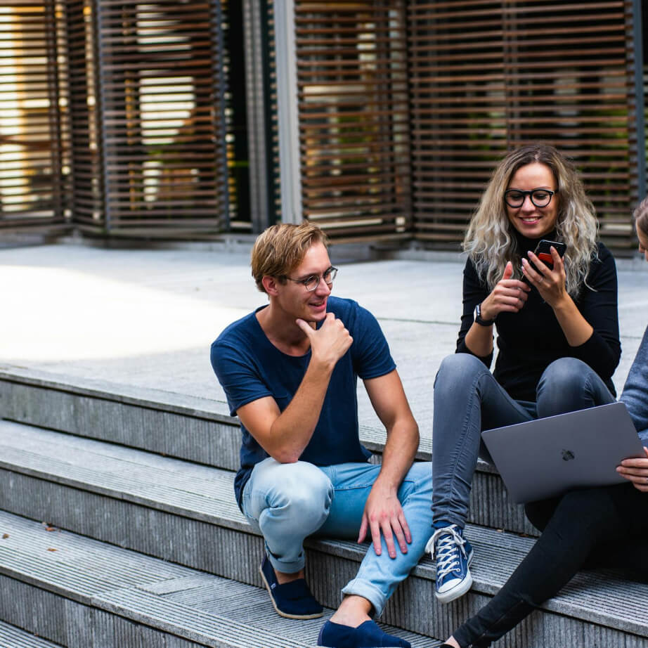 two young people sitting on stare working on laptop